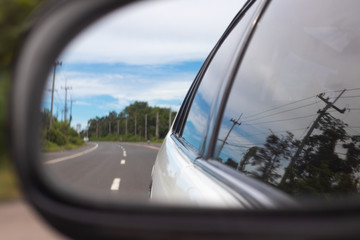 Naklejka premium Image reflected from the mirror of the car. See the road and the sky And trees along the way.