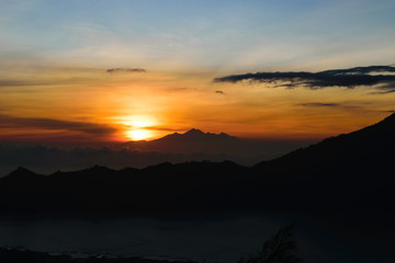 Early sunrise view from Gunung Batur volcano in Bali with visible silhouette of Rinjani mountains