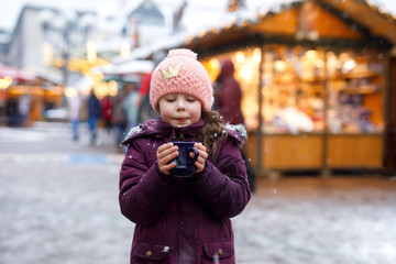 Little cute kid girl with cup of steaming hot chocolate or children punch. Happy child on Christmas...