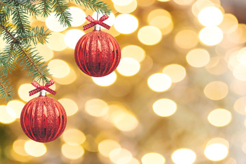 The branches of the Christmas tree are decorated with red balls on a golden background. Christmas festive background.