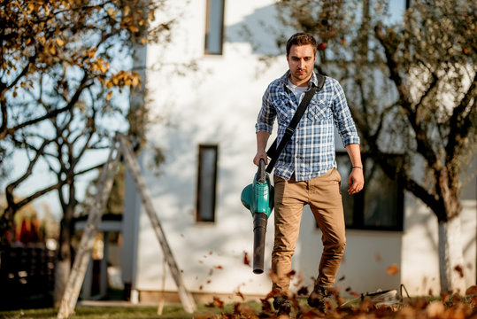 Portrait Of Worker Using Leaf Blower In Garden, Autumn Details