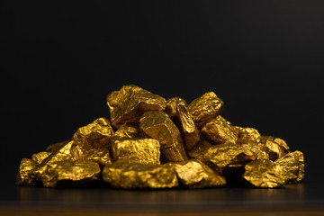A pile of gold nuggets or gold ore on black background, precious stone or lump of golden stone, financial and business concept.