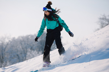 Woman snowboarder riding down from snowy hill