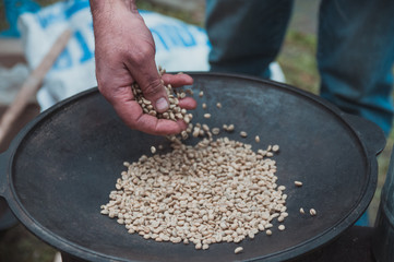 Traditional coffee beans roasting in metal basin with spoon
