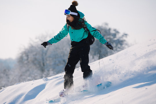 Woman snowboarder riding down from snowy hill