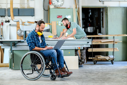 worker in wheelchair in a carpenter's workshop with his colleagu