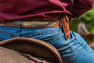 Lovely crafted belt and knife carrier and brown leather saddle, american cowboy warming up before...
