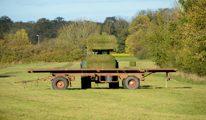 Bales of hay are being loaded on a trailer with a tractor.