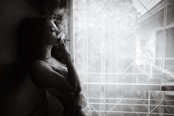 Schwarz-Weiß-Porträtfrau, die im Balkonzimmer raucht