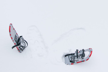 winter background, a pair of snowshoes inserted in fluffy white snow