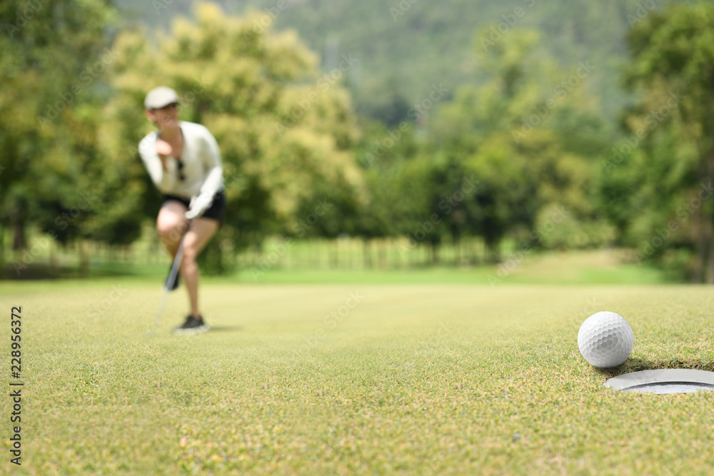 Wall mural Woman golfer cheering after a golf ball on a golf green