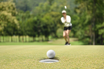 Woman golfer cheering after a golf ball on a golf green