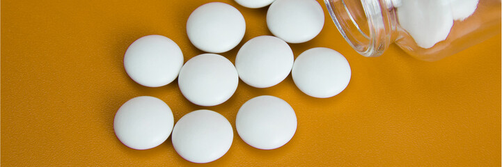 White tablets are scattered from a glass bottle.