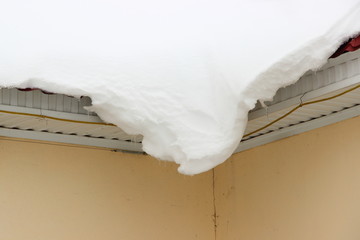 Snowdrift hanging from the roof down - cleaning of roofs from snow, municipal services, danger, winter