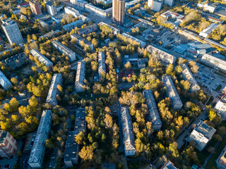 Obraz na płótnie Canvas Aerial view of a large number of residential buildings on the outskirts of the city on an autumn day during the Indian summer with the road and cars