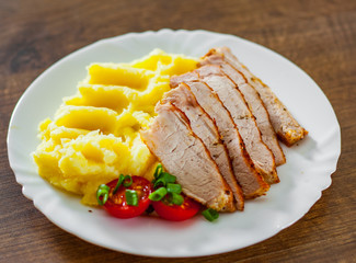 meat slices with mashed potatoes in white plate on wooden table background