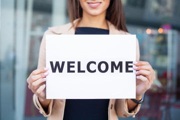 Businesswoman with long Hair Holding a sign Board with a Welcome has Airport Background