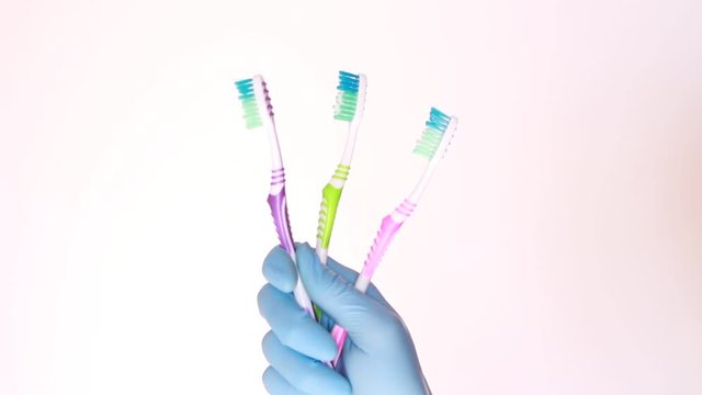 Holding three toothbrush in latex glove