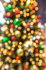 Colorful background of bokeh defocused christmas lights in several colors from a christmas tree with lights and xmas balls.