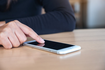 A woman using and touching smart phone on wooden table with blur background