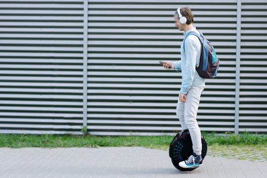 Modern young adult male businessman student freelancer riding driving on  ecological electric transport futuristic eco electric unicycle scooter,  balancing electric wheel with smartphone. Eco planet. Stock Photo | Adobe  Stock