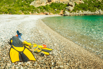 Flippers and snorkeling tube on sea shore