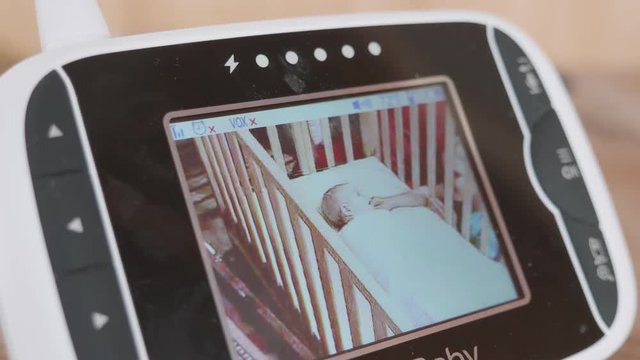 A Baby Monitor Showing Brother Playing With His Baby Sister