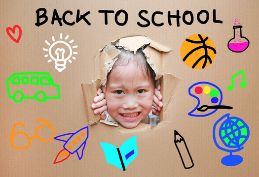 Little Asian kid girl looking through hole on cardboard with Back to school and education concept.