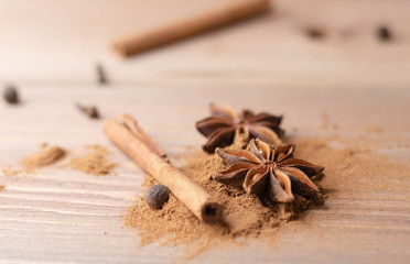 Cinnamon sticks, cinnamon powder, star anise closeup on wood