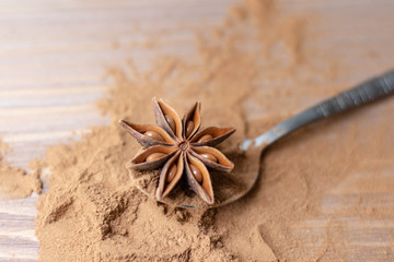 Cinnamon sticks, cinnamon powder, star anise closeup on the spoon. wood background