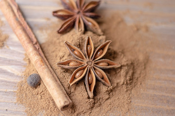 Obraz na płótnie Canvas Cinnamon sticks, cinnamon powder, star anise closeup on wood