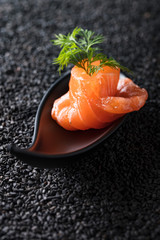 Salted salmon with dill on the background of black sesame.