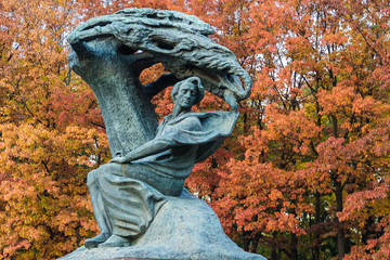 Monument to Fryderyk Chopin, famous Polish composer, in Royal Baths Park, the best-known Polish sculpture in the world by Waclaw Szymanowski on the red trees background. - 228962916