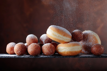 Sweet donuts powdered with sugar on a brown background.