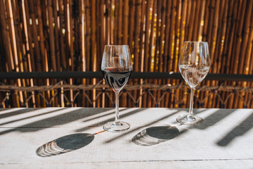 Two Glasses on the wooden table in a Hotel with bamboo wall with beautiful light and shadow