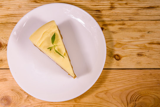 White plate with cheesecake New York on wooden table. Top view