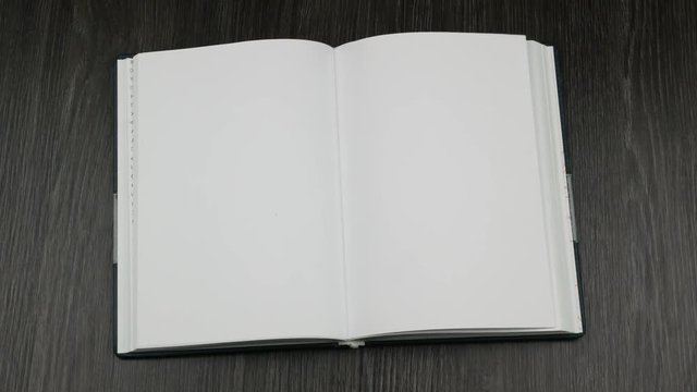 Hands putting an opened book on the table. Top view
