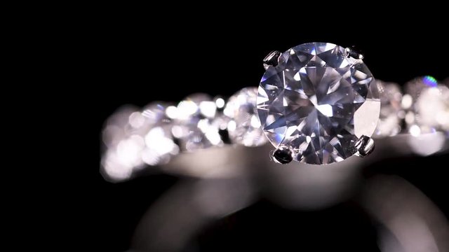 Engagement diamond ring rotating on black background, macro with shallow DoF