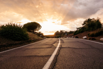 Low angle view of empty asphalt curvy road against sunset golden sky