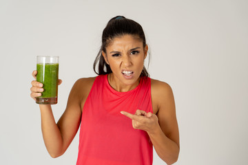 Beautiful young sport woman tired of diet holding green smoothie in dislike