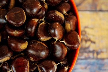 Chestnuts in an orange bowl with wooden background