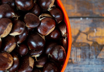 Chestnuts in an orange bowl with wooden background