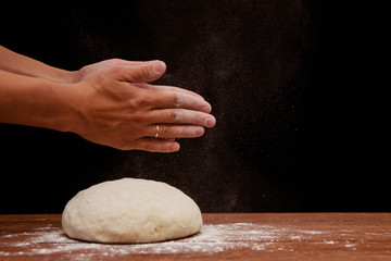 Obraz premium a lump of dough lie on a wooden table on a black background