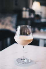  Homemade Milk Tea served in wine glass over white marble table with black and white blurred cafe background