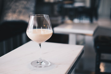  Homemade Milk Tea served in wine glass over white marble table with black and white blurred cafe background