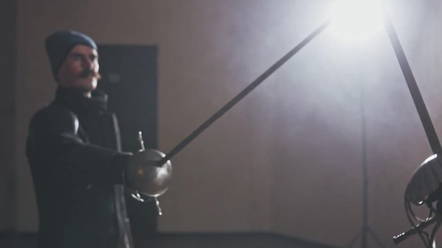 Medieval warriors training with swords indoors in slow motion.