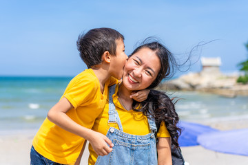 Asian mother and son enjoy relaxing on the beach © Danai