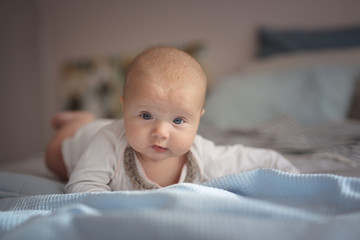 Baby on bed in nursery, lying on his stomach