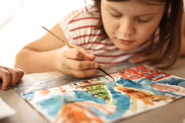 girl draws with brush and watercolors