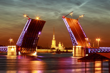 Fototapeta na wymiar Symbol of Saint-Petersburg, Russia. Summer white night. Raising of Palace bridge over river Neva. The reflection of the illumination in the water.